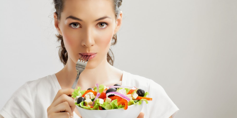 A Young Woman Holding A Bowl Of Fruits & Vegatables And Eating.