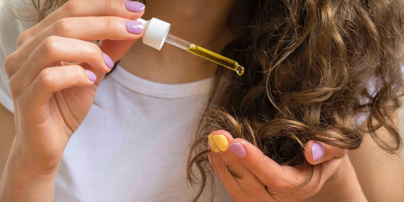 A Woman Pours A Single Drop of Hair Oil On Her Hand.