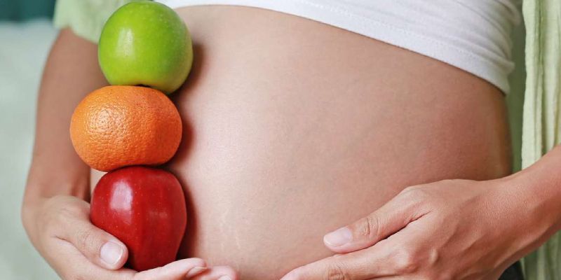 A Pregnant Woman Holding Fruits.